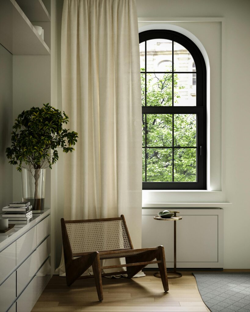 Elegant minimalist room with a wooden chair, potted plant, and arched window providing natural light.